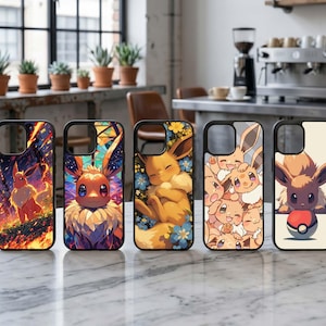 Op de afbeelding: Vijf zwarte telefoonhoesjes met kleurrijke Eevee-personageontwerpen. De hoesjes tonen verschillende scènes, waaronder Eevee in een bos, een portret in glas-in-loodstijl en Eevee die tussen bloemen slaapt. De hoesjes liggen op een marmeren oppervlak.