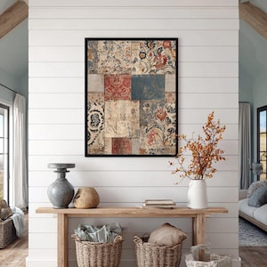 May include: A framed artwork with a patchwork design of floral and patterned fabrics in red, blue, and beige tones. The artwork hangs above a wooden console table with decorative baskets and a vase with dried branches.