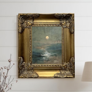 May include: A framed landscape painting with a gold ornate frame. The artwork depicts a moonlit scene over water, with a soft, muted color palette of blues, greens, and whites. The frame has detailed corner embellishments.