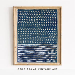 Könnte beinhalten: Ein gerahmtes Wandbild mit einem tiefblauen rechteckigen Druck, der im oberen Bereich ein Muster aus kleinen hellen Punkten und im unteren Bereich vertikale Striche aufweist, eingefasst in einen hellen Holzrahmen mit sichtbarer Maserung.