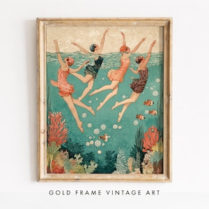 May include: A framed art print depicting four swimmers in vintage-style swimsuits submerged in teal water. The scene features coral reefs at the bottom, small orange fish, and bubbles rising toward the surface, all enclosed in a gold-toned frame.