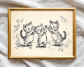 Könnte beinhalten: Ein gerahmter Druck mit einer Feder- und Tinte-Illustration von drei verspielten Kätzchen. Das Bild hat eine Vintage-Ästhetik, mit den Kätzchen in einem Feld aus Gras und Blumen. Der Rahmen ist goldfarben.