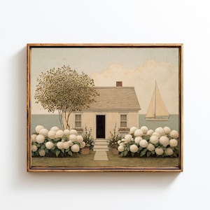 Puede incluir: Una impresión enmarcada que representa una casa de campo costera con un velero en el mar. La casa tiene un tejado gris y una puerta negra, con hortensias blancas en primer plano. La obra de arte está en un marco de madera.