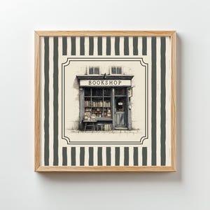 May include: A framed print featuring a detailed illustration of a quaint bookshop. The shop has a sign that reads "BOOKSHOP" above the entrance. The background has a striped pattern in shades of gray and white.