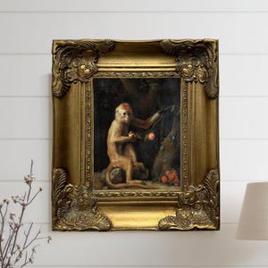 May include: A framed painting featuring a monkey in a natural setting. The artwork is set within an ornate, gold-colored frame. The monkey is depicted with a fruit in its hand, with other fruits at the base of a tree. The background is dark, with a hint of foliage.