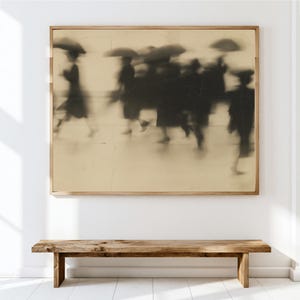 May include: A rectangular framed wall art piece featuring a sepia-toned, motion-blurred photograph of several figures walking with umbrellas. The image displays a grainy, vintage aesthetic with dark silhouettes against a light, textured background.