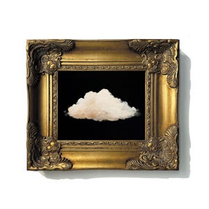 May include: A framed artwork featuring a fluffy, white cloud against a black background. The cloud is centered within the frame. The ornate, gold-colored frame has detailed carvings and a rectangular shape, adding a touch of elegance to the piece.