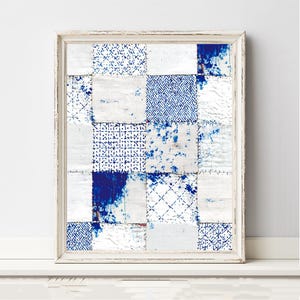 May include: A framed wall art piece featuring a grid of square fabric patches in shades of white and deep blue. The patches display various patterns including geometric lines, cross-hatching, and mottled ink-like splatters, all held in a white frame.