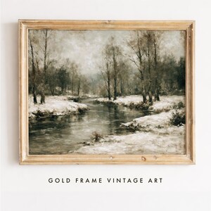 May include: A landscape painting in a gold frame depicting a winter scene with a flowing river, snow-covered banks, and bare trees under a muted, overcast sky. The artwork features a neutral colour palette of browns, greys, and whites.