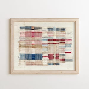 May include: A framed textile wall art piece featuring a woven grid pattern with horizontal and vertical threads in shades of red, blue, beige, and white. The design displays a loose, frayed appearance with visible thread ends and a light wood frame.