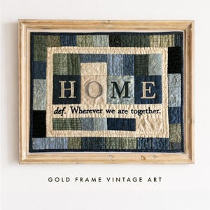 Puede incluir: Una pieza de arte textil enmarcada con un diseño de patchwork en tonos azul, verde y crema. El centro muestra la palabra HOME en letras grandes con el texto def. Wherever we are together. debajo, todo dentro de un marco de madera clara.
