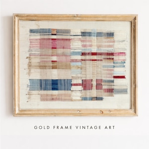May include: A rectangular wall art piece featuring a woven textile with a grid pattern of red, blue, and beige threads, displayed within a light-colored wooden frame. The fabric shows frayed edges and a layered, textured appearance with visible vertical and horizontal thread intersections throughout the composition.