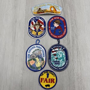 Può includere: Una collezione di sei toppe ricamate con vari disegni, tra cui un emblema del centenario dello Utah National Parks Council, due toppe Pow Wow 2000 con immagini scout, una toppa Pow Wow 2001, una toppa Pow Wow 2002 e una toppa gialla dello Utah Fair.