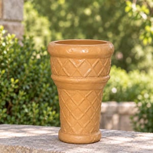 May include: A tan ceramic planter shaped like an ice cream cone, featuring a textured diamond grid pattern across the exterior surface, a wide circular opening at the top, and a thick, rounded base for stability on flat surfaces.