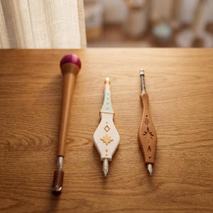 Può includere: Tre cacciaviti decorativi con manici ornati. Uno ha la parte superiore viola, il secondo è bianco con dettagli dorati e il terzo è marrone con disegni a stella. Tutti hanno punte in metallo.