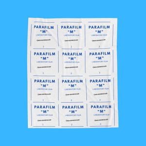 May include: A white rectangular blanket featuring a repeating grid pattern of blue text. Each square displays the words PARAFILM M LABORATORY FILM, the text BIOLOGVOBSESSED, and a number 1, 2, or 3. The design is printed on a soft fabric surface.