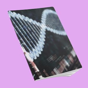 Könnte beinhalten: Ein rechteckiges Notizbuch mit einem dunklen Einband, der eine leuchtende, weiße Doppelhelix-DNA-Grafik zeigt. Das Design umfasst verschwommene, abstrakte Lichtmuster und dunkle Töne, wobei das Notizbuch aus einem Winkel dargestellt ist.