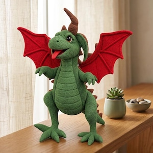 Pode incluir: Um dragão de pelúcia com corpo verde texturizado, grandes asas vermelhas e um chifre castanho na cabeça. A criatura tem a boca aberta com uma língua vermelha visível, olhos escuros e um design de barriga segmentado. Fica de pé sobre dois pés.