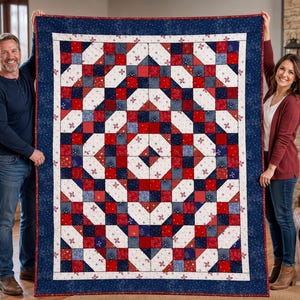 May include: A large, rectangular quilt with a patriotic design. The quilt features a pattern of red, white, and blue squares and geometric shapes. The border is a dark blue with a white floral pattern. The quilt is held up by two people.