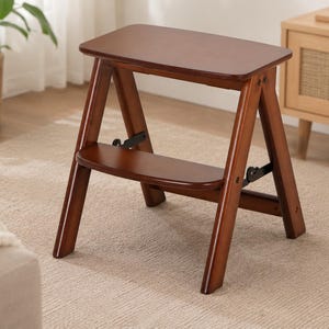 May include: A wooden step stool with a rich brown finish. The stool has a rectangular top and a lower step, supported by angled legs. The design is simple and functional, suitable for reaching higher shelves.