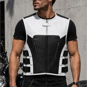 Male rider wearing a white and black leather motorcycle vest with zip pockets, center zipper and adjustable side straps.