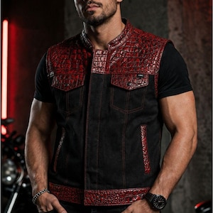 Male rider wearing a black motorcycle vest with glossy red croc-textured panels, chest pockets and red contrast stitching.