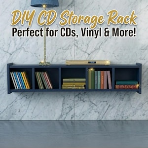 Può includere: Una mensola porta CD blu navy montata su un muro di marmo, piena di CD, vinili e libri. La mensola ha più scomparti e una piccola lampada. Il testo sull'immagine dice "DIY CD Storage Rack Perfect for CDs, Vinyl & More!"