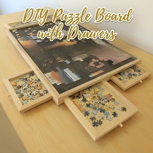 May include: A wooden puzzle board with drawers, featuring a partially assembled puzzle. The board has a dark stained surface and a light wood frame. Three drawers, also with light wood frames, are filled with puzzle pieces. Text on the image reads "DIY Puzzle Board with Drawers."