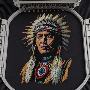 May include: An embroidered portrait of a Native American chief in a colorful headdress and traditional attire. The artwork is created with vibrant threads on a black fabric, showcasing detailed facial features and feather accents. The embroidery is framed by a silver hoop.