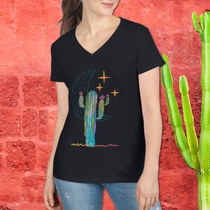 May include: A black V-neck t-shirt with a colorful cactus illustration and a crescent moon with stars. The cactus is green, blue, and purple with pink flowers.
