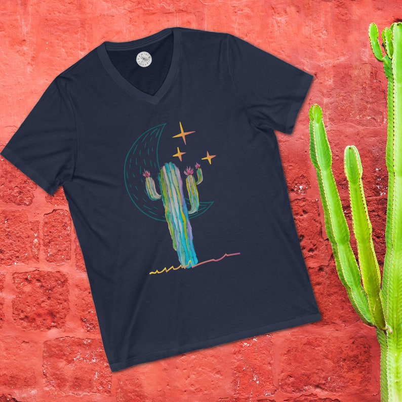 May include: A navy blue t-shirt with a graphic of a cactus with pink flowers under a crescent moon and stars.