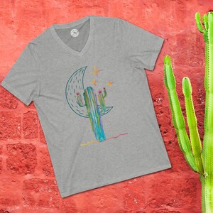 May include: A gray V-neck t-shirt with a graphic of a cactus in front of a crescent moon with stars. The cactus is green, blue, and purple with pink flowers.