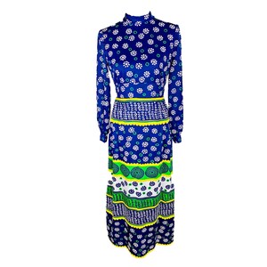 Puede incluir: Un vestido largo azul con estampado floral blanco y verde. El vestido tiene cuello alto y mangas largas.