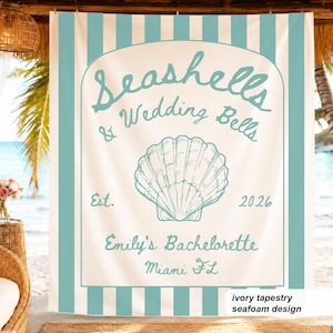 Op de afbeelding: Een rechthoekig stoffen wandkleed met verticale zeeschuimgroene en witte strepen. Het midden toont een witte boog met een zeeschuimgroene illustratie van een schelp en de tekst: Seashells & Wedding Bells, Est. 2026, Emily's Bachelorette, Miami FL.