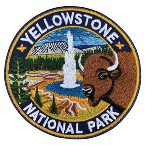 May include: Circular embroidered patch of Yellowstone National Park. The design features a geyser, bison, and landscape elements. The patch has the words "YELLOWSTONE NATIONAL PARK" in a curved font around the edge. The colour palette includes blue, green, brown, and white.