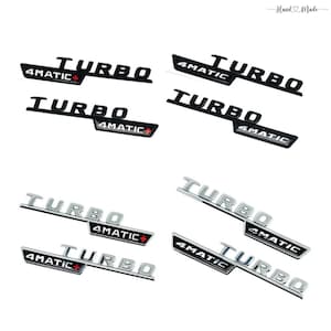 May include: A collection of car emblems featuring the words "TURBO" and "4MATIC" in black and silver. The emblems have a sleek, modern design, with a red plus sign on the "4MATIC" emblem. The words "Hand Made" are written in cursive at the top.