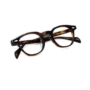 May include: Tortoiseshell-patterned eyeglasses with a rounded frame shape, featuring silver-toned diamond-shaped accents on the outer corners of the frame front and clear lenses. The inner temple arm displays the text 1954 and other markings.