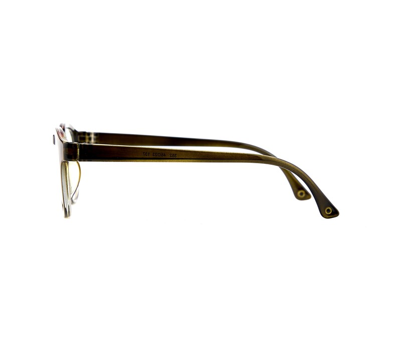 May include: A pair of eyeglasses with a translucent olive green frame viewed from the side. The temple arm features a visible hinge and a small circular metallic detail at the tip. The frame displays the printed text 51 17-140 136 on the inner side.