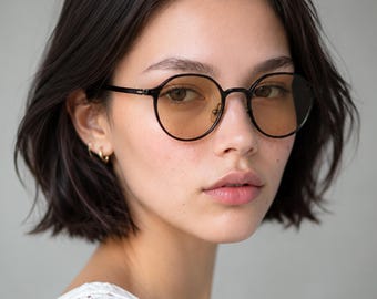 May include: Round-framed glasses with thin black metal rims and light amber-tinted lenses. The eyewear features a classic bridge design and slender temples, providing a clear view of the circular frame shape and the warm, translucent lens color.