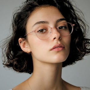 May include: Round eyeglasses with a translucent, pale pink frame and thin, matching temples. The glasses feature a classic circular shape with a bridge and nose pads, providing a clear view of the lenses and the frame's lightweight construction.