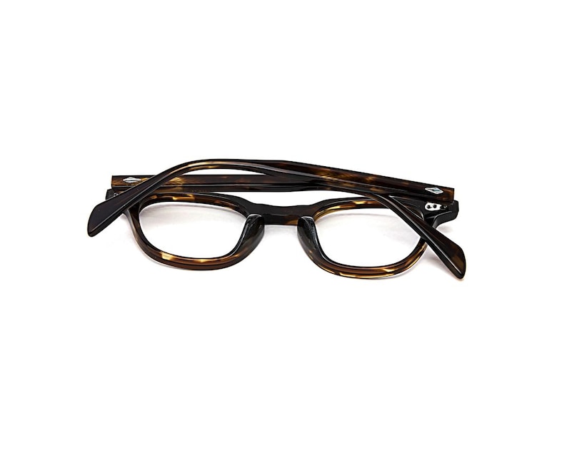 May include: Tortoiseshell eyeglasses with a dark brown and amber mottled pattern. The frames feature a rounded rectangular shape with a keyhole bridge and silver-toned diamond-shaped rivets on the front corners and temples.