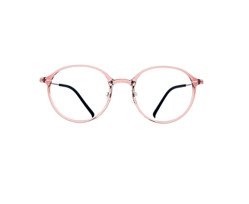May include: Round eyeglasses featuring a translucent, light pink plastic frame. The glasses have a thin bridge and slim, dark-colored temple arms that extend from the sides of the circular rims, providing a clear view of the lenses.
