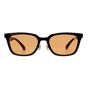 May include: Black-framed sunglasses with amber-tinted lenses. The rectangular frames have a subtle curve at the top and feature a small silver detail near the hinges. The temples are curved and black.