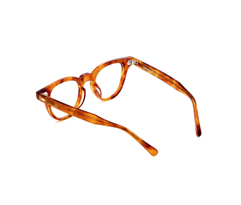 Puede incluir: Gafas con estampado de carey. Las monturas son de color marr&oacute;n c&aacute;lido con vetas marrones m&aacute;s oscuras. Las gafas tienen una forma redonda cl&aacute;sica. La imagen muestra las gafas sobre un fondo blanco.