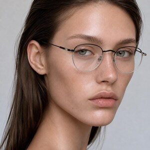May include: Eyeglasses featuring a thin, black metal frame with a rounded, oval-shaped lens design. The frame includes delicate, slender temples and adjustable nose pads, providing a lightweight and minimalist appearance for the wearer's face.