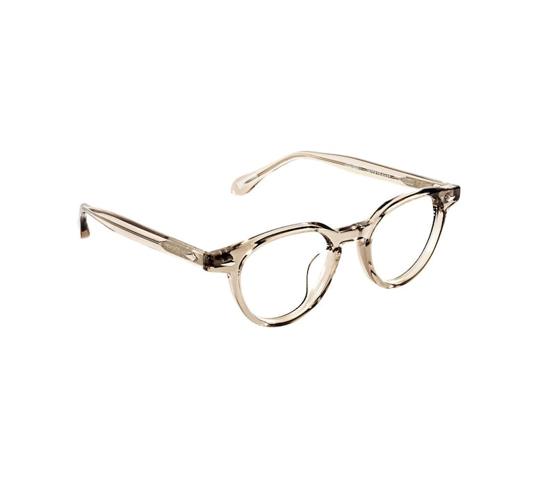 May include: A pair of round-framed eyeglasses with a translucent, light brown frame. The glasses have a classic design, with thin temples and a bridge. The lenses are clear, and the overall aesthetic is modern and minimalist.
