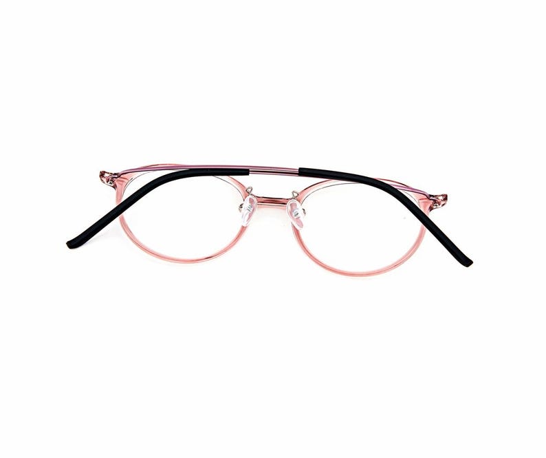May include: Eyeglasses featuring a translucent pink frame with a thin double bridge design. The temples are finished with black rubberized tips, and the clear lenses are held within rounded rims, creating a lightweight and functional eyewear piece.
