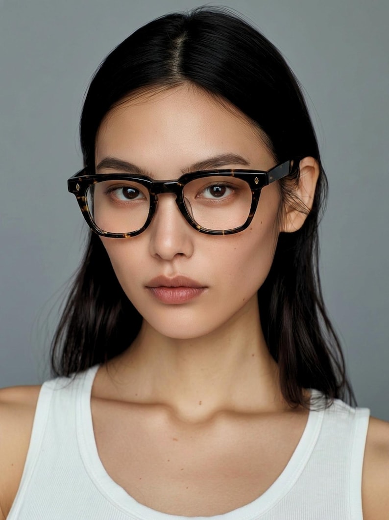 Puede incluir: Gafas de montura cuadrada con estampado de carey. Las gafas tienen una combinaci&oacute;n de colores marr&oacute;n oscuro y negro, con peque&ntilde;os detalles en forma de diamante en las patillas. Las lentes son transparentes y la montura es gruesa y resistente.