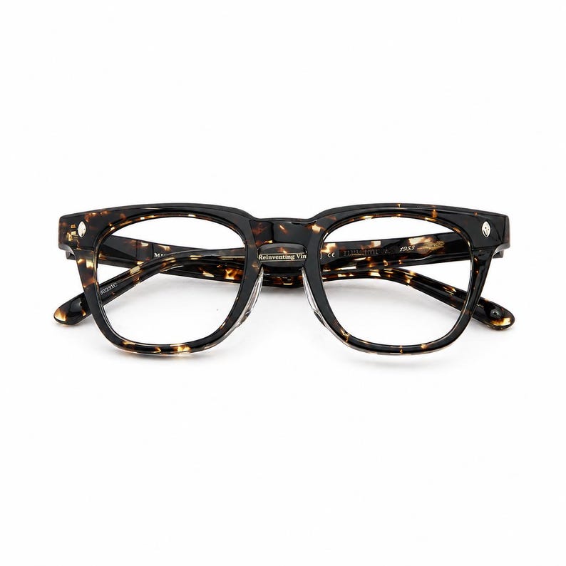Puede incluir: Gafas de montura cuadrada con estampado carey. Las monturas son negras y marrones con un dise&ntilde;o moteado. Las lentes son transparentes. El texto "Reinventing Vintage" es visible en la montura.