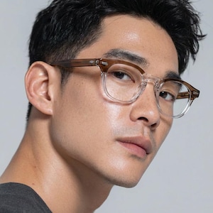 May include: Clear-framed eyeglasses with brown temples. The glasses have a square shape and are worn by a person. The image is a close-up shot, highlighting the details of the eyewear.
